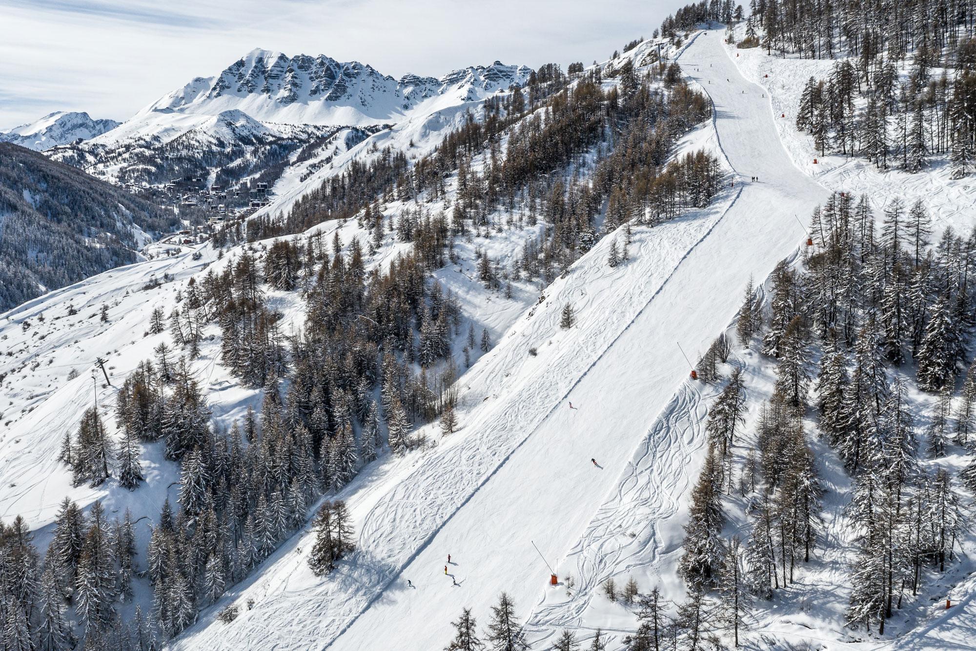 Skiiers enjoying long ski slope in French Alps at Vars ski resort